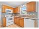 Functional kitchen featuring granite countertops, wooden cabinetry, and white appliances at 3313 Summit Creek Ln, Loganville, GA 30052