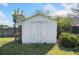 View of the backyard storage shed with double doors and lattice trim, surrounded by lush greenery and grass at 3313 Summit Creek Ln, Loganville, GA 30052