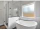 Bright bathroom features a glass enclosed shower and separate soaking tub beneath a frosted window at 2317 Pleasant Grove Rd, Temple, GA 30179