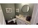 This powder room features a granite vanity, round mirror, art prints, and toilet at 2317 Pleasant Grove Rd, Temple, GA 30179