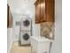 Well-lit laundry room featuring a stacked washer and dryer, utility sink, and custom cabinet storage at 746 Amsterdam Ave, Atlanta, GA 30306