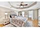 Comfortable bedroom featuring a tufted headboard, decorative pillows, patterned bedding, and a tray ceiling with a fan at 1712 Green Farm Cir, Dacula, GA 30019