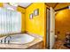 Bright bathroom showcasing a tiled soaking tub and access to toilet room at 290 Leigh Kay Dr, Lawrenceville, GA 30046