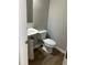 A small bathroom with a white pedestal sink and toilet on a dark floor at 295 Laurelton Cir, Lawrenceville, GA 30044