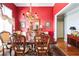 Dining room featuring bold red walls, hardwood flooring, a large window, and decorative chandelier at 1490 Highland Lake Dr, Lawrenceville, GA 30045