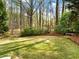 Serene backyard with a mature lawn, featuring mature trees, and a stone bench at 1544 Blue Bird Way, Cumming, GA 30041