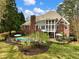 View of home's backyard with in-ground pool, brick exterior, large deck, and mature trees at 1544 Blue Bird Way, Cumming, GA 30041