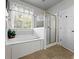 Bright bathroom features a jacuzzi tub next to a window and a separate glass door shower at 1544 Blue Bird Way, Cumming, GA 30041