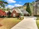 Charming brick home featuring a well-manicured lawn, mature trees, and a long driveway leading to a two-car garage at 1544 Blue Bird Way, Cumming, GA 30041