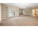 Expansive living area with plush carpeting, built-in shelving, and access to the outdoors at 1544 Blue Bird Way, Cumming, GA 30041