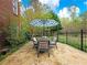 Outdoor stone patio showcasing a dining table with umbrella and views of the lush backyard at 1544 Blue Bird Way, Cumming, GA 30041