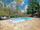 Inviting in-ground pool area with stone patio, lounge seating, and wooded views at 1544 Blue Bird Way, Cumming, GA 30041