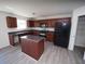 Well-lit kitchen with an island, dark cabinetry, stainless appliances, and wood-look flooring at 7267 Appaloosa Cv, Fairburn, GA 30213