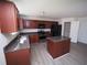 Kitchen with island, dark cabinets, stainless appliances, and wood-look flooring, and walk-in pantry at 7267 Appaloosa Cv, Fairburn, GA 30213