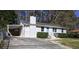 Cozy single-story home with a carport, white siding, and manicured front yard with trees behind it at 810 Commodore Nw Dr, Atlanta, GA 30318