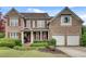 Charming brick two-story home with red shutters, well-manicured landscaping, and a welcoming front porch at 179 Bradshaw Park Dr, Woodstock, GA 30188