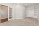 Neutral living room featuring a large built-in bookshelf and cabinet, carpeted floor, and glass doors to another room at 507 Grove Field Ct, Suwanee, GA 30024