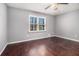 Bright bedroom with dark hardwood floors, a neutral gray paint scheme, a large window, and a ceiling fan at 570 Knollwood Dr, Stockbridge, GA 30281