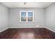 Bright bedroom with dark hardwood floors, a neutral gray paint scheme, a large window, and a ceiling fan at 570 Knollwood Dr, Stockbridge, GA 30281