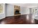 Open-concept living room with a stone fireplace, gleaming hardwood floors, and a view of the backyard at 570 Knollwood Dr, Stockbridge, GA 30281