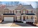 Charming two-story home with stone accents, shutters, a covered front porch, an attached garage, and a well-manicured lawn at 9645 Dunhill Way, Cumming, GA 30028