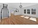 Open-concept living room features hardwood floors, staircase, a kitchen view, and large windows for natural light at 9645 Dunhill Way, Cumming, GA 30028
