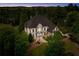Aerial dusk view of house surrounded by tall trees; inviting landscape lighting at 19 Troup Ct, Acworth, GA 30101