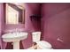 Stylish powder room with pedestal sink, elegant mirror, and dark purple walls at 50 Biscayne Nw Dr # 5112, Atlanta, GA 30309