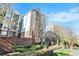 Upscale condominium with brick facade, balconies, lush landscaping, and a clear blue sky at 50 Biscayne Nw Dr # 5112, Atlanta, GA 30309
