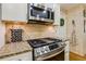 Kitchen details include stainless steel range, granite counters, and brick accent wall at 215 Morning Glory Rdg, Canton, GA 30115