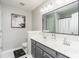 Modern bathroom with double sinks, gray cabinetry, a framed mirror and chic black and white flower painting at 2449 Suwanee Pointe Dr, Lawrenceville, GA 30043