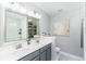 Bathroom with dual sinks, gray cabinetry, large mirror and a shower-tub combination with decorative elements at 2449 Suwanee Pointe Dr, Lawrenceville, GA 30043