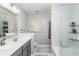 Bright bathroom featuring dual sinks, gray cabinets, a combination shower and tub, and stylish marble tile surround at 2449 Suwanee Pointe Dr, Lawrenceville, GA 30043