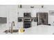 Kitchen with stainless steel appliances, white cabinets, gray backsplash, and white countertops at 2449 Suwanee Pointe Dr, Lawrenceville, GA 30043