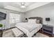 Comfortable bedroom features a tray ceiling, a ceiling fan, and soft natural light from the window at 2449 Suwanee Pointe Dr, Lawrenceville, GA 30043