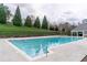 Outdoor pool with steel railing, green grassy hill, and community clubhouse at 2449 Suwanee Pointe Dr, Lawrenceville, GA 30043