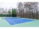 View of the community tennis court, with green and blue surface, with surrounding trees at 2449 Suwanee Pointe Dr, Lawrenceville, GA 30043