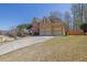 Side view of two-story home featuring a three-car garage, stone accents, and an expansive driveway at 1621 Telfair Chase Way, Lawrenceville, GA 30043