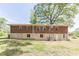 Rear view of the property showing an expansive backyard, large mature trees, and a partially fenced area at 1157 Helen St, Morrow, GA 30260