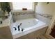 Spacious soaking tub with jets and a neutral tiled surround with decorative accents near a window at 1520 Camden Cove Dr, Cumming, GA 30040
