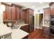 Well-lit kitchen with stainless steel appliances, custom wood cabinetry, and granite countertops by staircase at 1520 Camden Cove Dr, Cumming, GA 30040