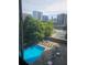 Upper-level view of a community pool with lounge chairs surrounded by lush trees and high rise buildings at 215 Piedmont Ne Ave # 304, Atlanta, GA 30308