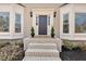 A welcoming front entrance with a gray door, brick steps, decorative plants, and sidelight windows at 2018 Sugar Maple Ln, Woodstock, GA 30189