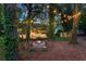 Secluded backyard with hammock and fire pit surrounded by lush trees with string lights at 3851 Westwick Nw Way, Kennesaw, GA 30152