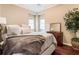 Comfortable bedroom featuring a queen-sized bed, bedside table, mirror, nearby windows, and a potted tree at 3851 Westwick Nw Way, Kennesaw, GA 30152