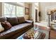 Spacious living room featuring a brown leather sofa, glass coffee table, nearby windows, and a nearby staircase at 3851 Westwick Nw Way, Kennesaw, GA 30152