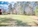 A lush, verdant lawn slopes down towards a house nestled amongst tall trees at 5190 Paul Sw Cir, Conyers, GA 30094