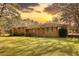 Sunset view of sprawling ranch-style home with a lush green lawn and mature trees at 5190 Paul Sw Cir, Conyers, GA 30094