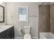 Well-lit bathroom featuring a stylish vanity, toilet, and modern tiled shower with a glass door at 928 Gate Post Ln, Lawrenceville, GA 30044