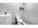 Modern bathroom featuring grey tiled walls, dark grout, a toilet, and vanity sink at 1484 Highland Bluff Ct, Suwanee, GA 30024